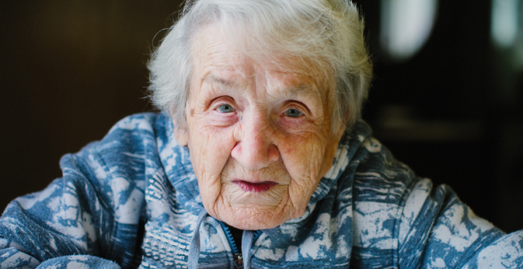 Old woman seated looking at the camera with her hands crossed