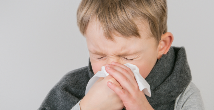 Young boy blowing his nose into a handkerchief