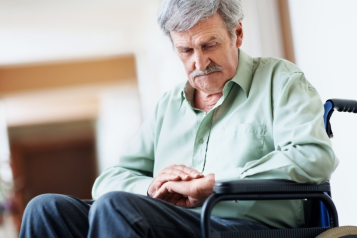 Man sat in wheelchair looking down at his hands