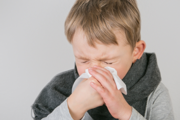 Young boy blowing his nose into a handkerchief