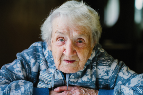 Old woman seated looking at the camera with her hands crossed
