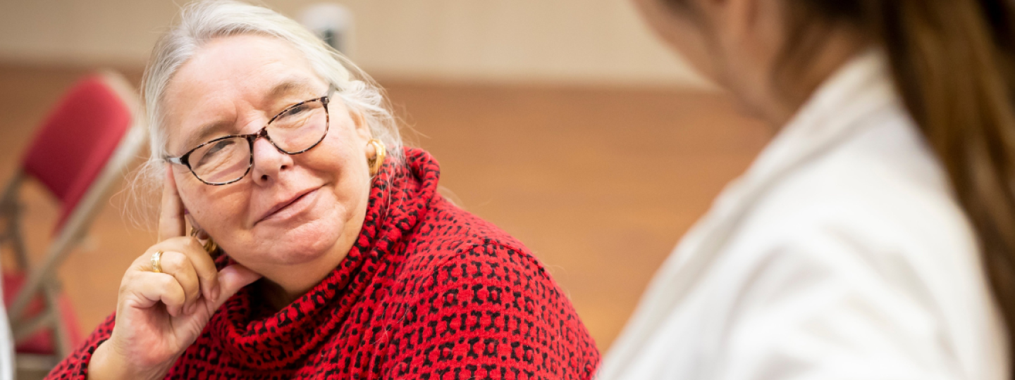 Older woman seated smiling at another woman