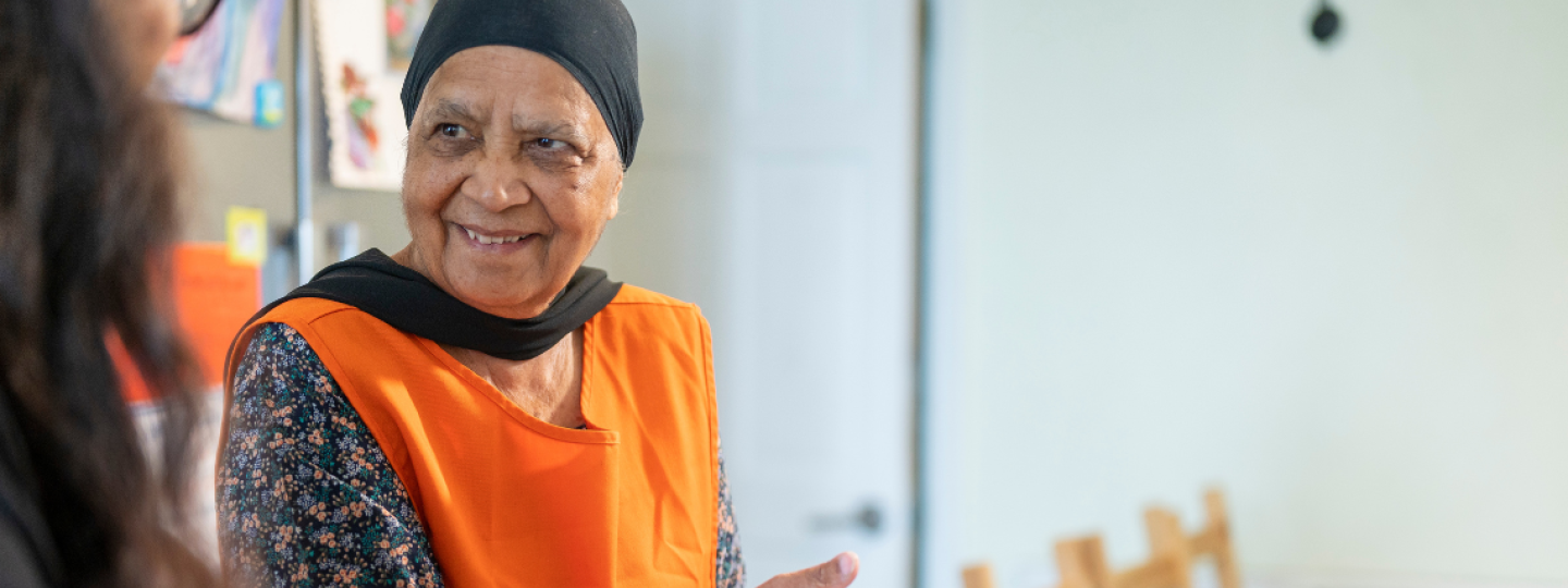 Older woman seated smiling at another woman