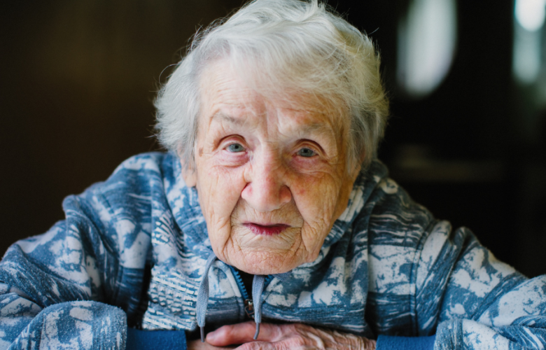 Old woman seated looking at the camera with her hands crossed