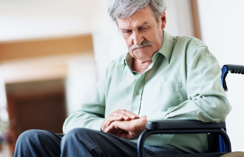 Man sat in wheelchair looking down at his hands